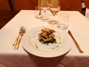 a white plate of food on a table with wine glasses at Albergo Cappello in Ravenna