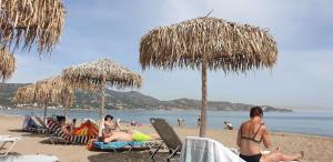 a group of people sitting on the beach under straw umbrellas at Amoudara Suites in Amoudara Herakliou