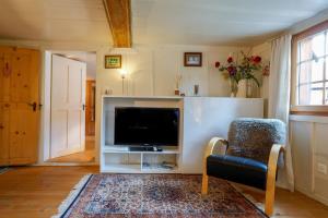 ein Wohnzimmer mit einem TV und einem Stuhl in der Unterkunft Apartment Werlen in Münster VS