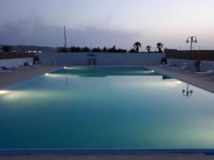 una piscina vacía por la noche con luces encendidas en Hotel Villa Damanti, en Licata