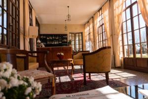 a living room with chairs and a table and windows at Hotel Villa Cornér Della Regina in Vedelago