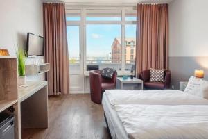 a hotel room with a bed and a large window at Kappen Plambeck in Heiligenhafen