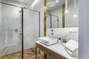 a white bathroom with a sink and a shower at Homewell Boutique Apartments in Poznań