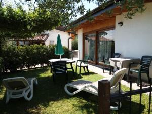 un patio con sillas, mesas y una sombrilla verde en B&B Camister, en Toscolano Maderno
