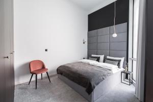 a bedroom with a bed and a red chair at Homewell Boutique Apartments in Poznań