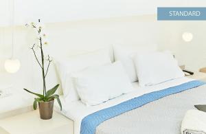 プリノスにあるInspira Boutique Hotel - Adults Onlyの白い枕と鉢植えの植物が備わる白いベッド