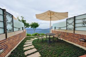a patio with a table and chairs and an umbrella at Ming Ging Farm in Renai