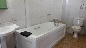 a bathroom with a tub and a toilet and a sink at Hotel Dot Com Entebbe in Entebbe +37 photos