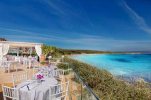a restaurant with white tables and chairs on the beach at Hotel Dei Pini in Alghero
