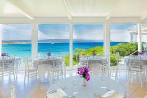 a dining room with tables and chairs and the ocean at Hotel Dei Pini in Alghero