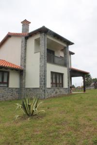 una casa grande con un patio con una planta delante en El Limonero de Pría - Casa Vacacional en La Pesa