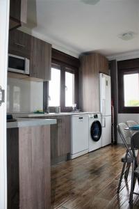 La cuisine est équipée d'un réfrigérateur blanc et d'un lave-vaisselle. dans l'établissement El Limonero de Pría - Casa Vacacional, à La Pesa