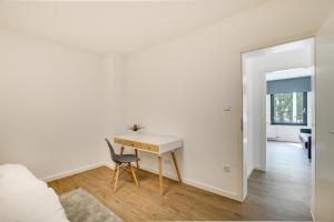a white bedroom with a desk and a chair at Stay Here ND Apartments in Krefeld