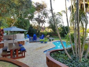 a backyard with a swimming pool with a table and a bench at The Hillcrest Guesthouse in East London