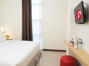 ジャカルタにあるd'primahotel Melawai - Blok Mのベッドルーム(白いベッド1台、赤い椅子付)
