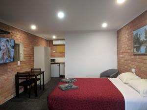 Habitación de hotel con cama roja y cocina en Travellers Inn Kaniva en Kaniva