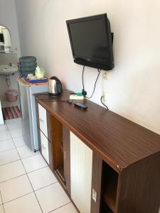 a flat screen tv on a wall with a wooden counter at RedDoorz near Pantai Barat Pangandaran 2 in Pangandaran