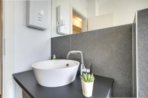 ein Badezimmer mit einem weißen Waschbecken auf einer schwarzen Theke in der Unterkunft Stay Here ND Apartments in Krefeld
