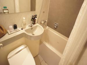 a white toilet sitting next to a sink in a bathroom at Nishitetsu Inn Shinjuku in Tokyo
