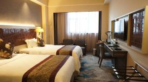 Cette chambre comprend deux lits, un bureau et une télévision. dans l'établissement Shenzhen Lido Hotel, à Shenzhen