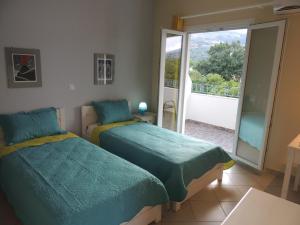 two beds in a room with a balcony at levante studios Αndros in Ménites