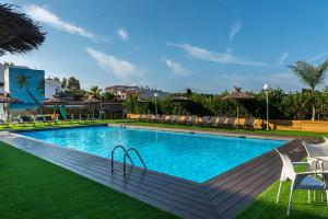 a large swimming pool with chairs on the grass at Apartaments Els Llorers in Lloret de Mar