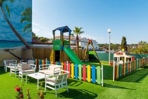 a playground with a slide and chairs on the grass at Apartaments Els Llorers in Lloret de Mar