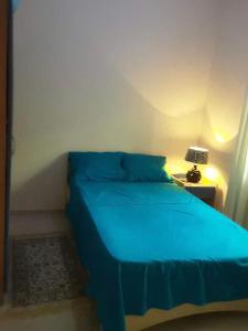 een blauw bed in een kamer met een lamp op een tafel bij Dunes ressort chott Meriem in Sousse