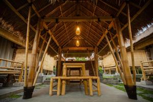 een paviljoen met een tafel en stoelen onder een dak bij Salty Shakas Bamboo Stay Canggu in Canggu