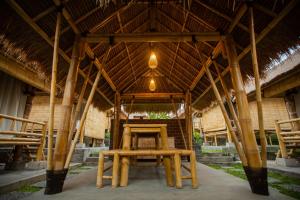 a pavilion with a table and chairs under a roof at Salty Shakas Bamboo Stay Canggu in Canggu