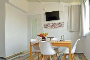 uma sala de jantar com uma mesa de madeira e cadeiras brancas em Museum loft apartment, with city view. em Heraclião