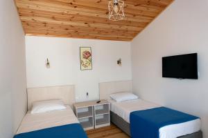 a bedroom with two beds and a tv on the wall at Metins Gümüşlük in Bodrum City