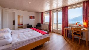 1 dormitorio con 1 cama, escritorio y ventanas en Hôtel Splendide en Crans-Montana