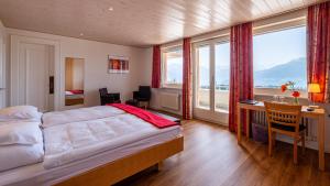 a bedroom with a bed and a desk and windows at Hôtel Splendide in Crans-Montana