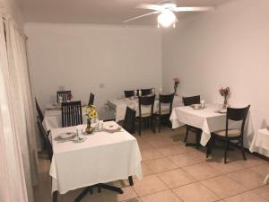 a dining room with white tables and black chairs at YoIeli Guest House in Windhoek
