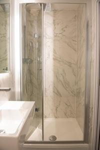 a shower with a glass door next to a sink at Messina Studios in London