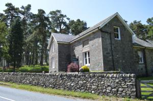 una casa de piedra con una pared de piedra junto a una carretera en The Farmhouse B&B, en Dunkeld