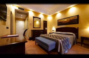 a bedroom with a bed and a dresser and a desk at Artemis Hotel in Cefalù