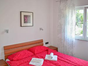 a bedroom with a red bed with two towels on it at Apartment Jadranka-3 by Interhome in Rab