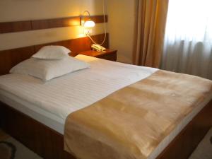 ein Schlafzimmer mit einem großen weißen Bett mit einer Lampe in der Unterkunft Hotel Crisana Arad in Arad