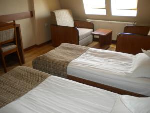 a hotel room with two beds and a chair at Hotel Crisana Arad in Arad