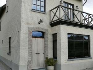 a white brick house with a wooden door at Cozy Holiday Home in Aalter near Lake in Maria Aalter