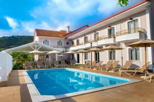 un hotel con piscina, sedie a sdraio e ombrelloni di Caretta - Caretta Hotel a Ligia