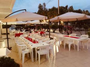 a group of tables and white chairs and umbrellas at Tindari Village Camping in Furnari