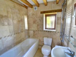 a bathroom with a tub and a toilet and a sink at Holiday Home Palmerston Barn by Interhome in Haverfordwest