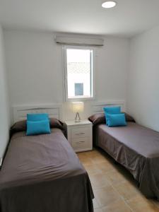 two beds in a room with a window at VILLA DIPLOMADO (RELAX EN EL PARAISO) in Es Mercadal