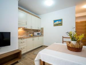 a kitchen with white cabinets and a table and a tv at Apartment Oltari-1 by Interhome in Biljevine