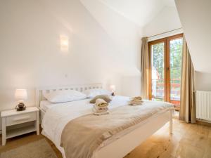 a white bedroom with a bed and a window at Apartment Oltari-2 by Interhome in Biljevine