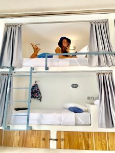 a woman is sitting on top of a bunk bed at Seaesta Komodo Hotel & Hostel in Labuan Bajo +47 photos