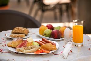 two plates of food on a table with fruit and orange juice at Eagles Philadelfia in Korçë
